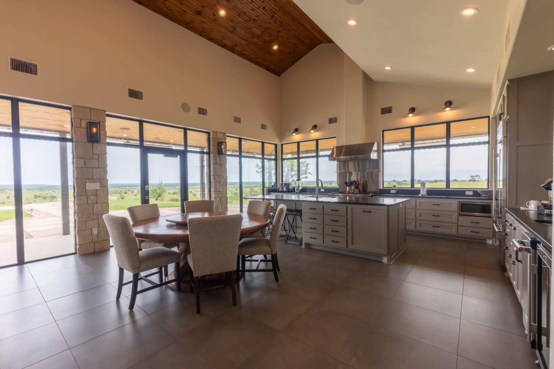 Guest House dining area with round table and floor-to-ceiling windows — Trinity Valley Ranch Deer, Coleman Texas
