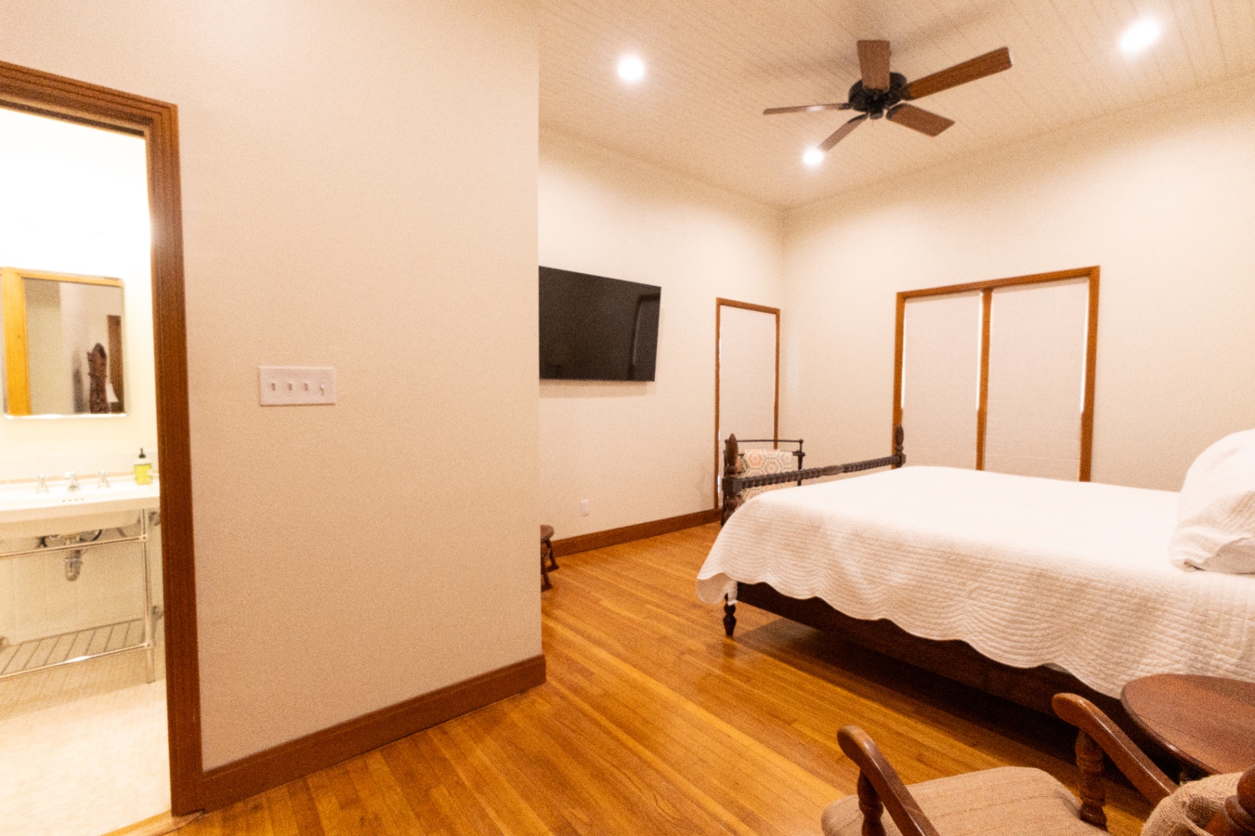 Farm House bedroom with iron bed, hardwood floors, and en-suite bath — Trinity Valley Ranch Deer, Coleman Texas