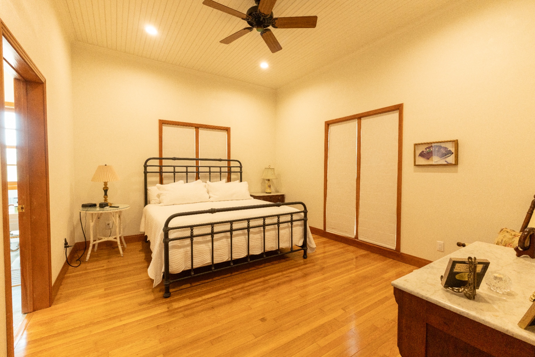 Farm House queen bedroom with iron bed frame and hardwood floors — Trinity Valley Ranch Deer, Coleman Texas