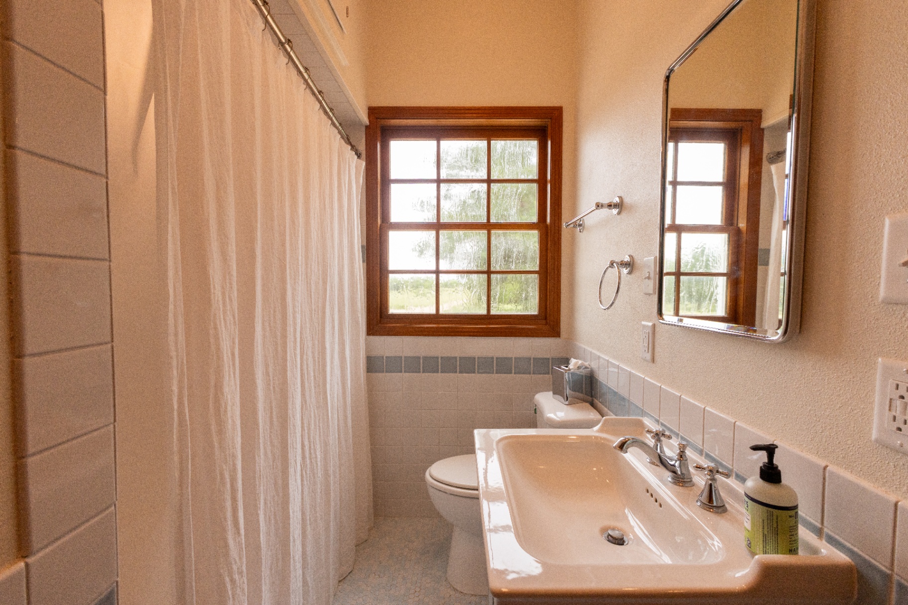 Farm House bathroom with pedestal sink, garden window, and tub shower — Trinity Valley Ranch Deer, Coleman Texas