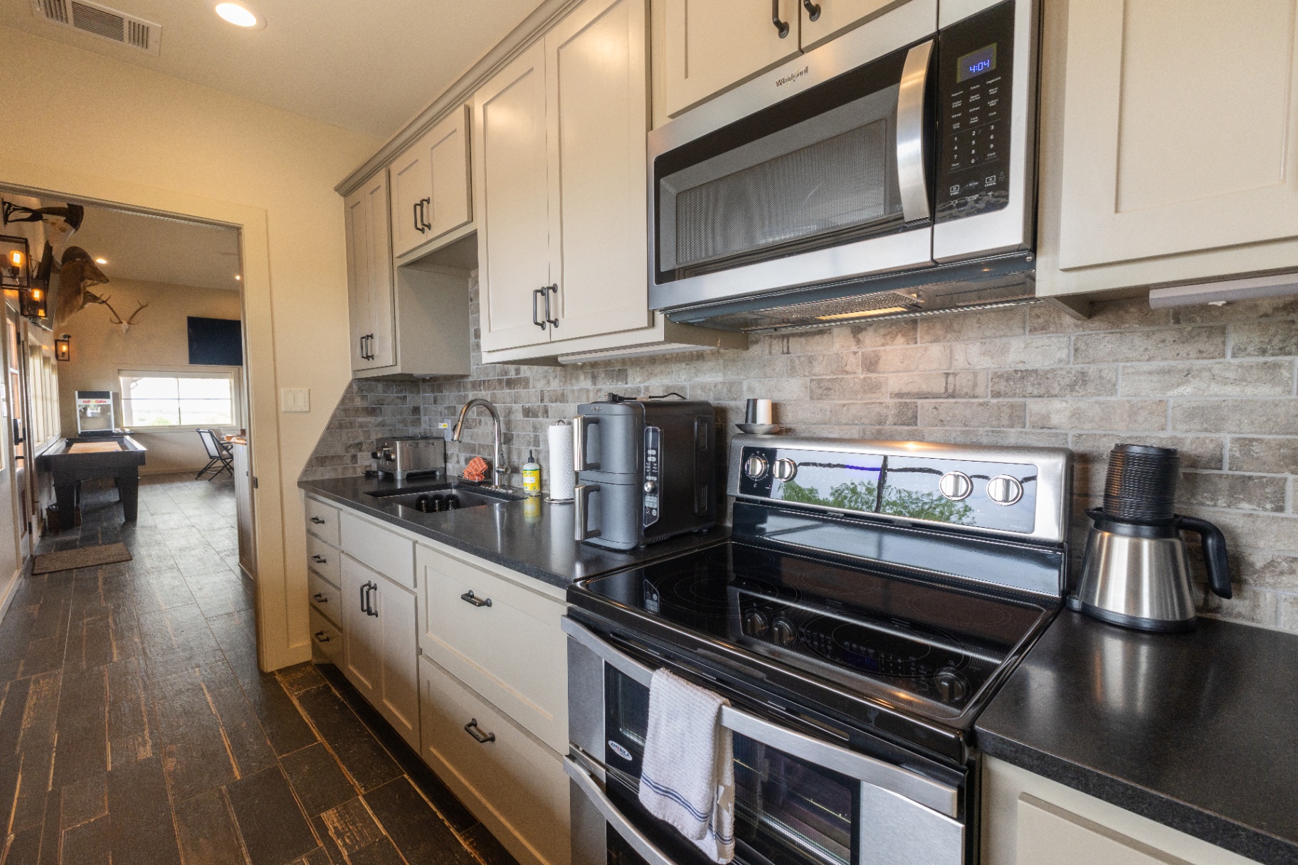 Saloon kitchenette with range, microwave, and prep space — Trinity Valley Ranch Deer, Coleman Texas