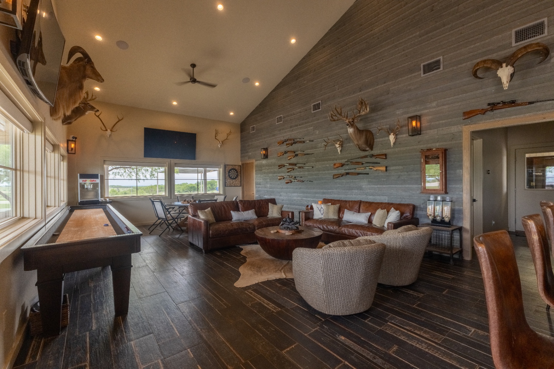Saloon lounge with leather seating, shuffleboard, and trophy wall — Trinity Valley Ranch Deer, Coleman Texas