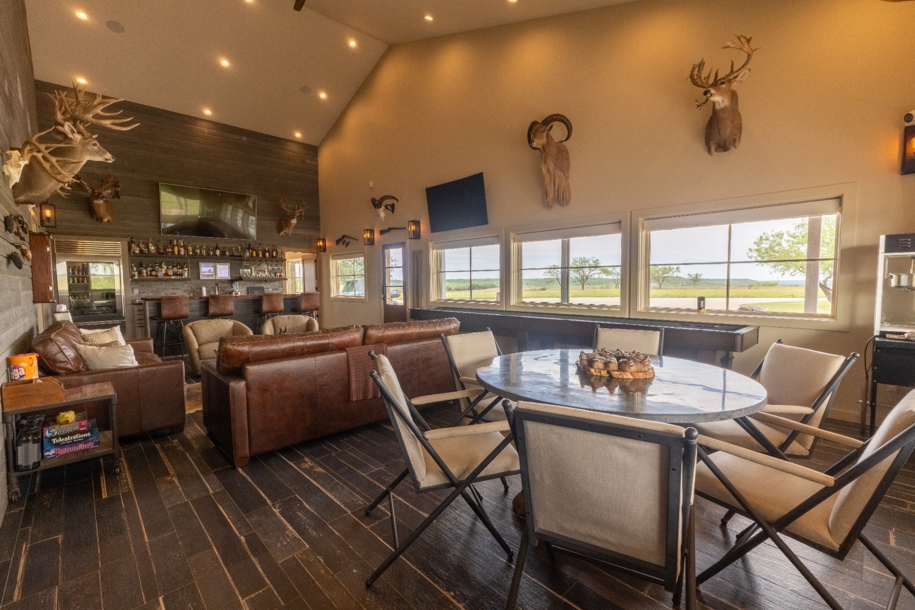 Saloon lounge with oval card table and bar in background — Trinity Valley Ranch Deer, Coleman Texas